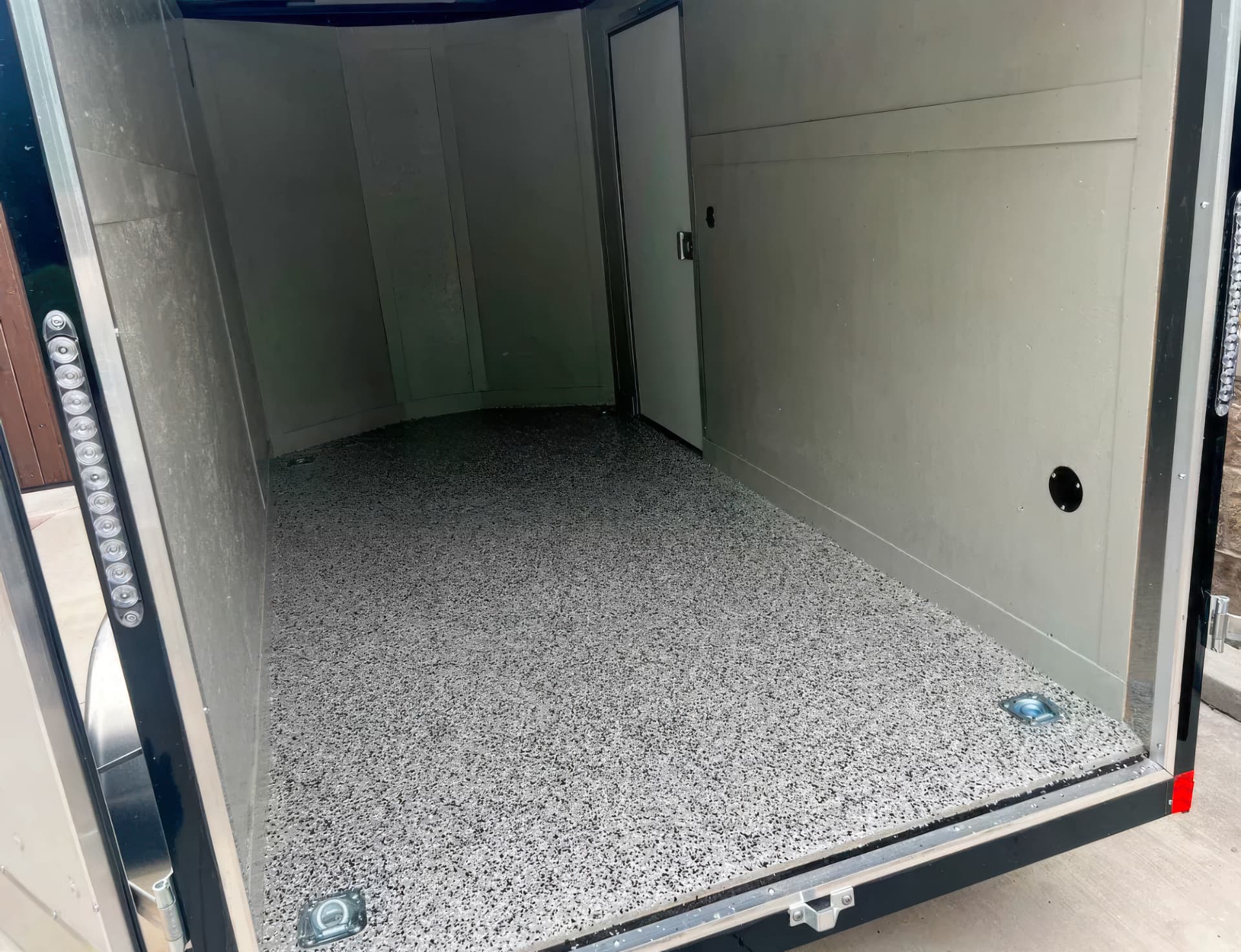 Gray flake floor coating installed in an enclosed cargo trailer.